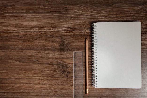 Notebook and pencil on wooden background