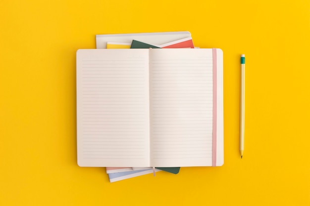 Notebook and pencil on yellow background