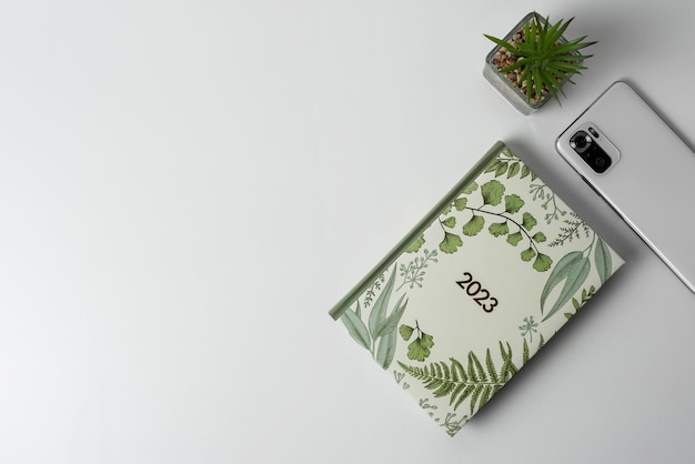 A notebook a plant and a smartphone on a light background