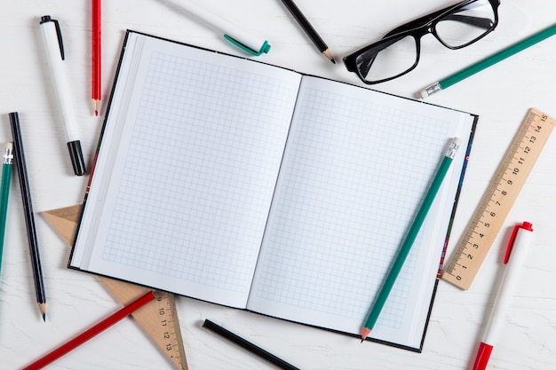 Notebook, potloden, linialen, glazen, markeringen op de witte tafel, kopie ruimte.