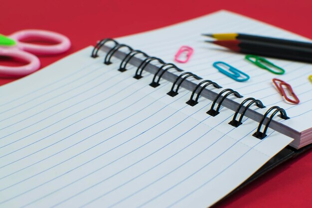 Notebook potlood, papier houder, schaar, school briefpapier op rode achtergrond. Terug naar school