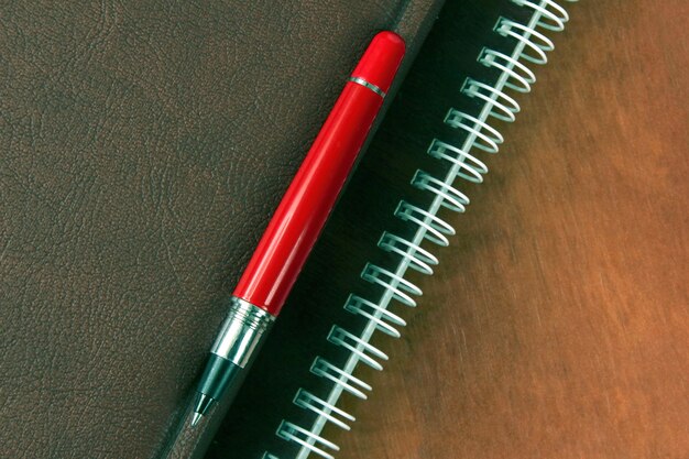 The notebook and a red pen lying on wooden desk