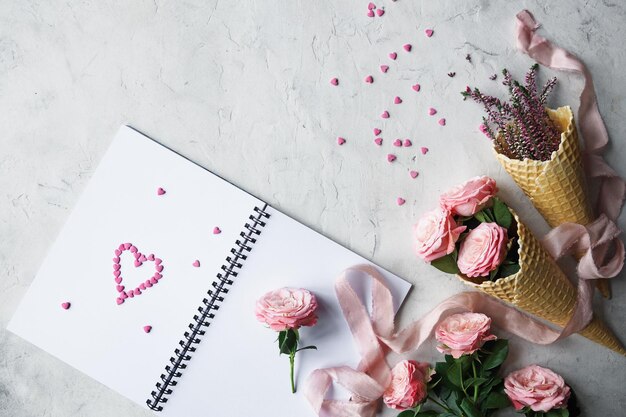 Notebook rozen roze lint en zoete snoepjes in de vorm van hart op witte achtergrond decoratie voor Valentijnsdag of bruiloft dag kaart bovenaanzicht plat lag selectieve aandacht