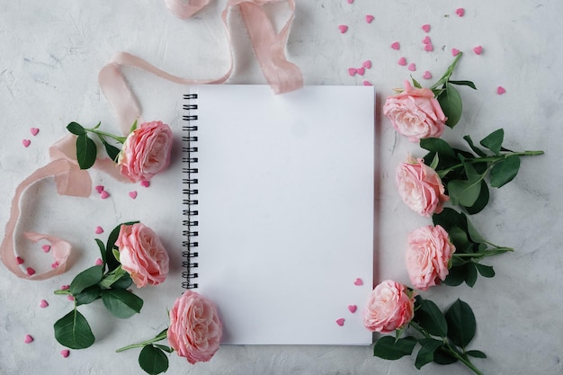 Notebook rozen roze lint en zoete snoepjes in de vorm van hart op witte achtergrond decoratie voor Valentijnsdag of bruiloft dag kaart bovenaanzicht plat lag selectieve aandacht