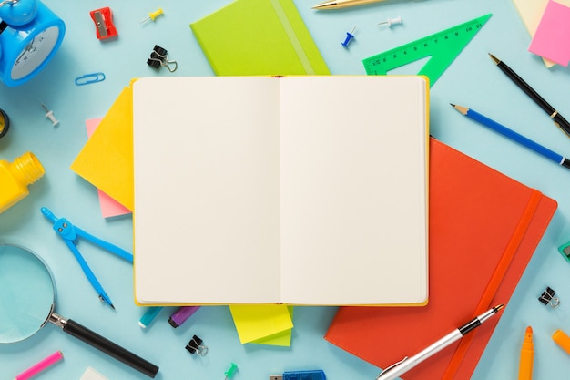 Notebook and school accessories at abstract background surface