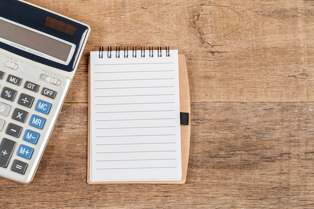 Notebook showing empty page  and calculator on wooden desk