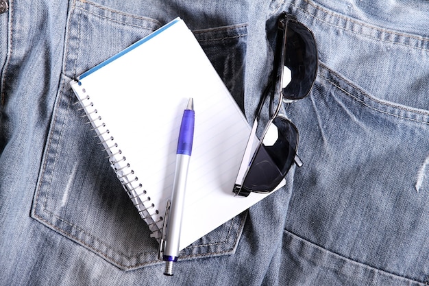 A notebook on some jeans trousers.