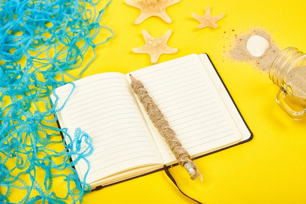 Notebook, starfishes and seashells, glass with sand