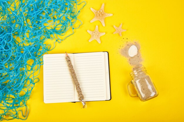 Notebook, starfishes and seashells, glass with sand