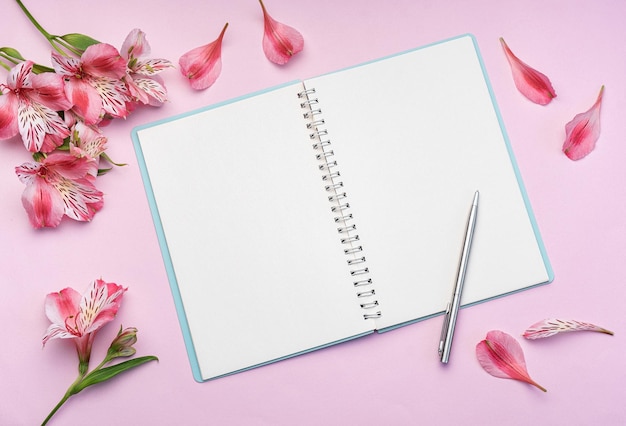 The notebook surrounded by pink Alstroemeria flowers and petals