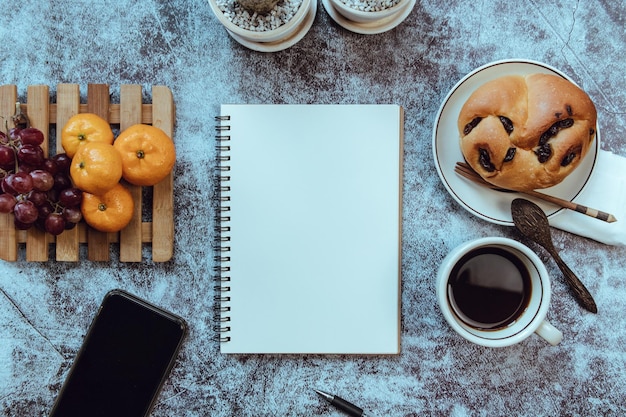 Photo notebook on the table there is breakfast placed on the side top view