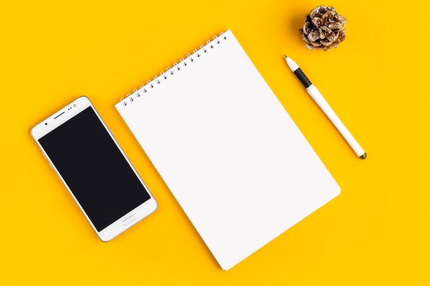 Notebook, telefoon, mobiel, thee, pen, bril op een gele achtergrond