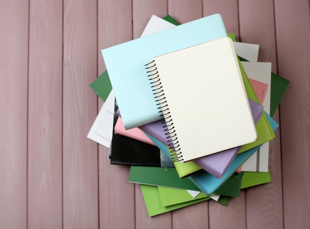 Photo notebook on top of pile of books and magazines on wooden background