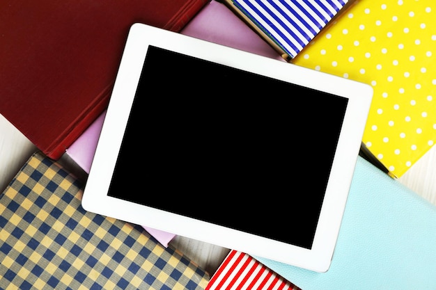 Notebook on top of pile of books on wooden background