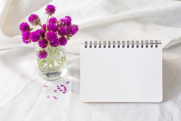 Notebook and violet flower on table