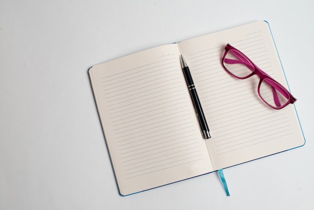 Notebook with black pen and glasses