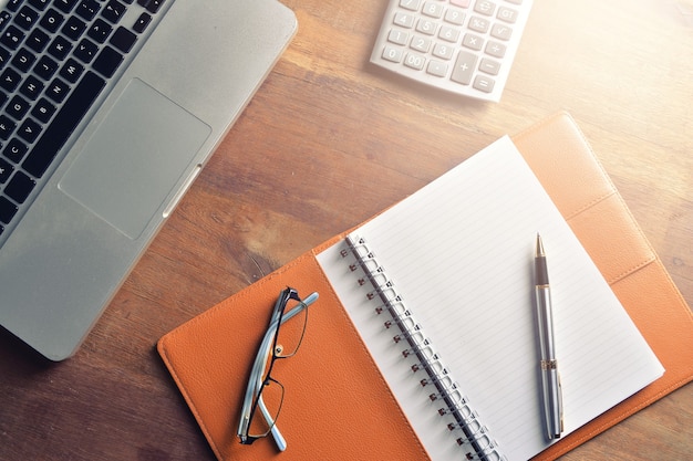 Notebook with calculator, keyboard and pen on table