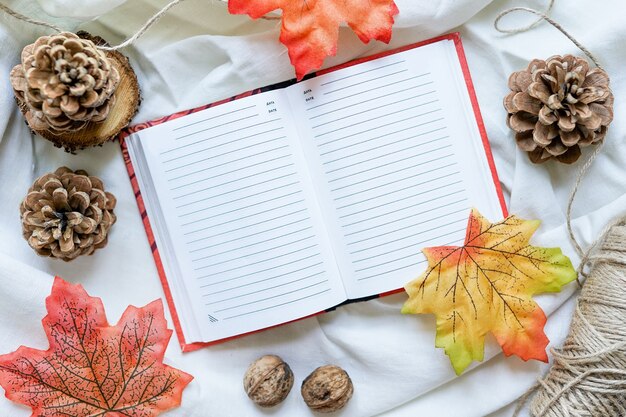 明るい紅葉を背景にきれいなシーツのノート。秋の気分のコンセプト。フラットレイ、上面図、コピースペース