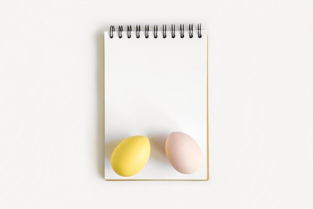 Notebook with Easter Eggs Spiral notepad on spring white background Top view of open writing pad