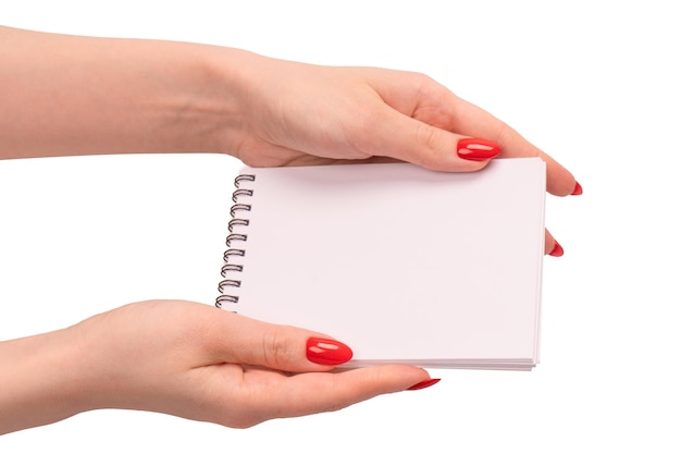 A notebook with empty white paper in woman hands with red nails