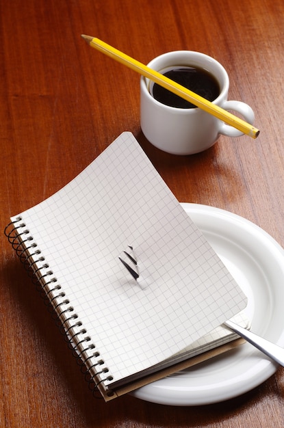 Notebook with a fork on a plate and cup of coffee