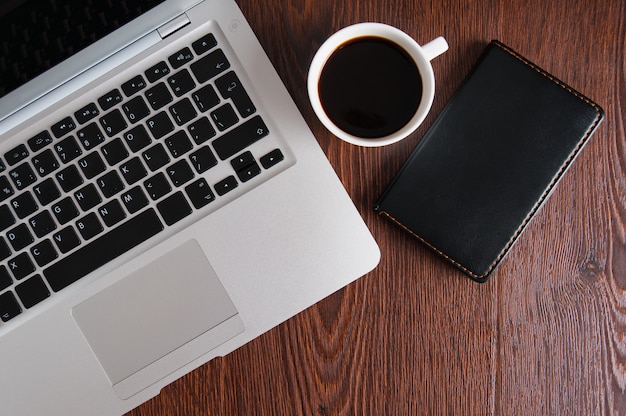 Notebook with hot coffee on wood table