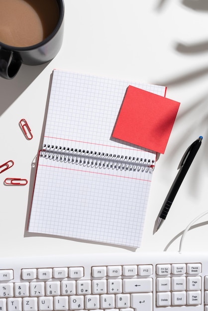 Notebook with important messages on both sides on desk with coffee pen paperclips keyboard and