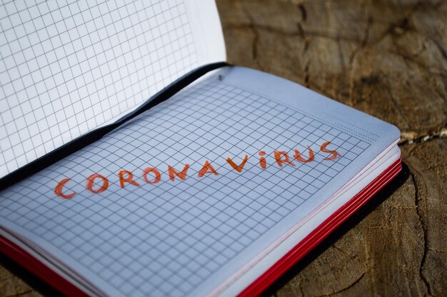 切り株にコロナウイルスの碑文が書かれたノートブックコロナウイルスとCovid19をテーマにしたコンセプト写真