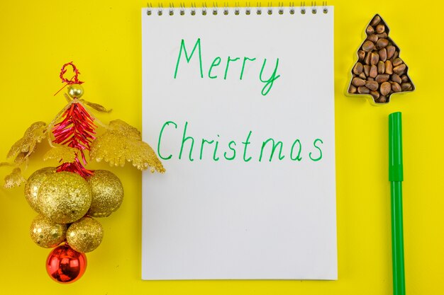 Notebook with the inscription Merry Christmas on the background of New Year's decorations.