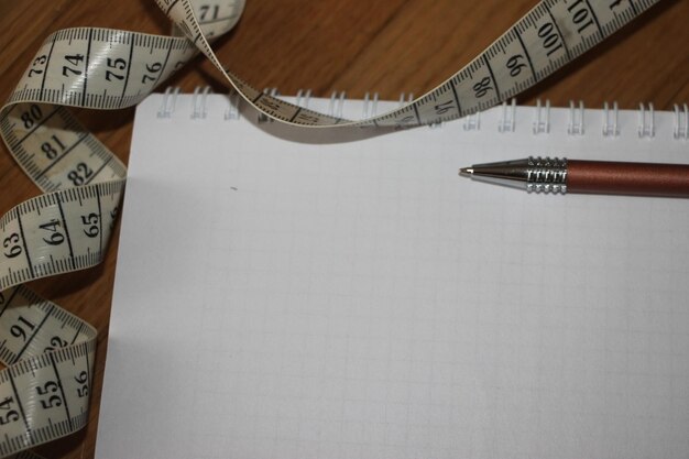 A notebook with measurement tape and a pen planning a diet\
healthcare concept