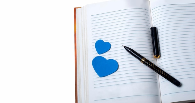 Notebook with pen and blue hearts isolated on white background love concept