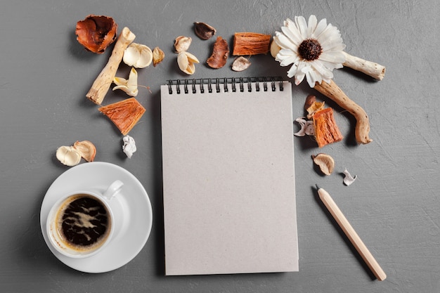 Notebook with pen, coffee and flower on table