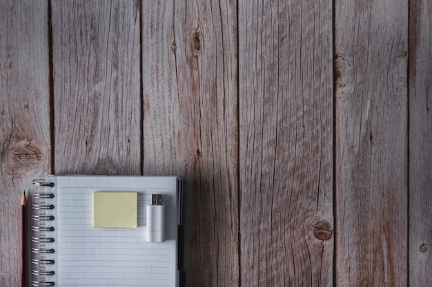 Notebook with pen notes and USB flash drive on wooden background Top view Copy space Selective focus