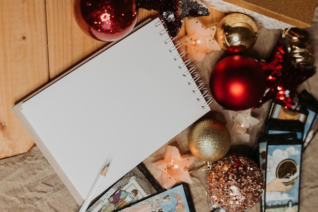 A notebook with a pen sits on a table next to a christmas decoration.