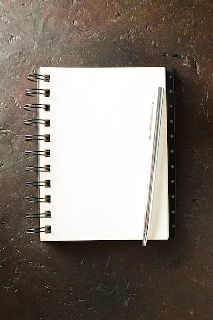 Notebook with pencil on brown background