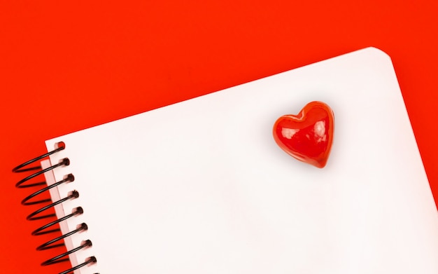 빨간색 하트가 있는 노트북, 빨간색 테이블과 복사 공간이 있는 연애 편지 배경 개념, 위쪽 보기 사진