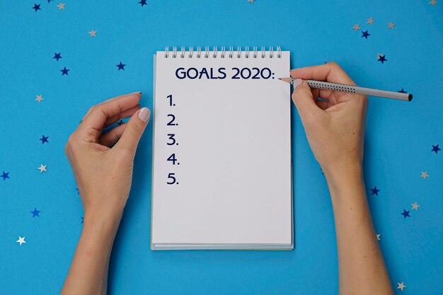 Фото Блокнот с текстом цели 2020 и женские руки с карандашом