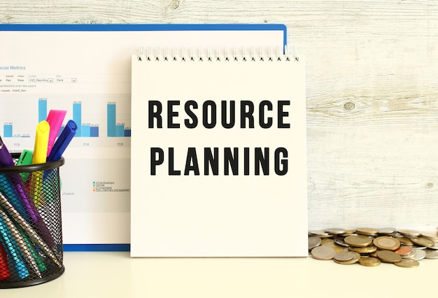 RESOURCE PLANNINGというテキストのノートブックは、チャートのあるフォルダーで壁にもたれかかっています。