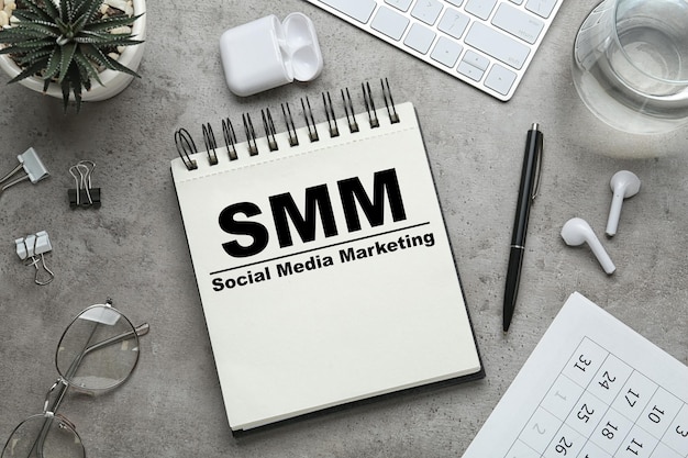 テキスト SMM ソーシャル メディア マーケティングと灰色のテーブル フラット レイアウト上の他のオブジェクトとノートブック
