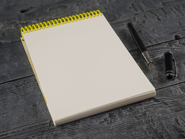 Photo notebook with yellow cover and black fountain pen on a wooden table.