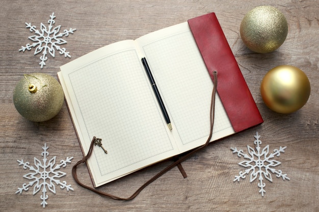 Notebook on wooden table, New year's decoration and christmas balls, Copy space for notes.