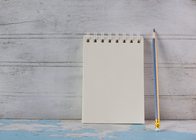 Notebook and yellow pencil on vintage blue wooden table background