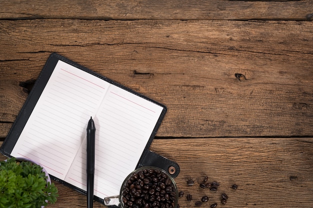 Notebook e tazza di caffè in grani posti su un tavolo in legno vista dall'alto