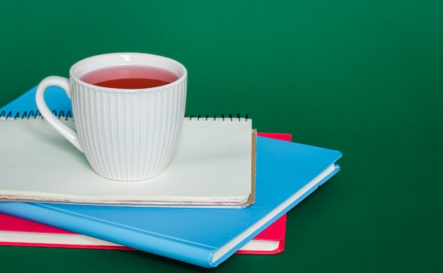 Notebooks and a cup of tea on a green background the concept of work and study