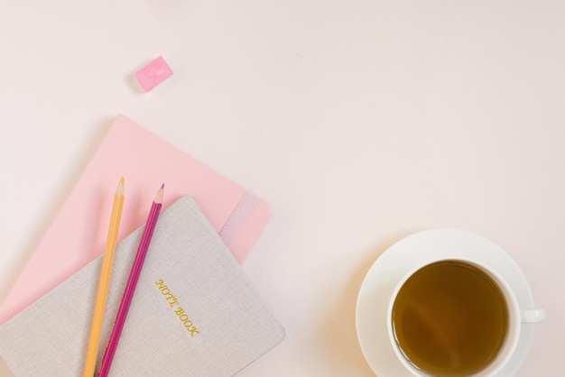 Notebooks kleurpotloden een kopje thee op een beige achtergrond met een kopie ruimte Workplace