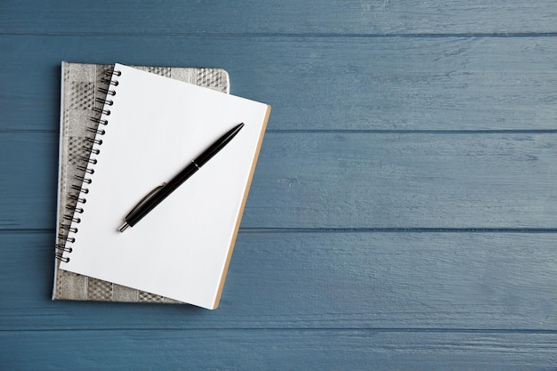 Notebooks and pen on blue wooden table top view Space for text