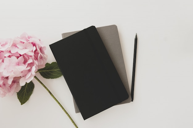 Notebooks, pencil and pink hydrangea flower.