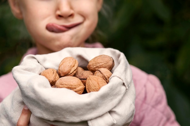 Noten Walnoot voor Kind met Tong uit. Walnoten oogsten. Biologische voeding voor kinderen. Koptische ruimte.