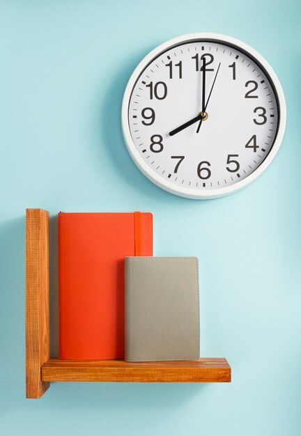 Notepad and book on shelf at wall background surface