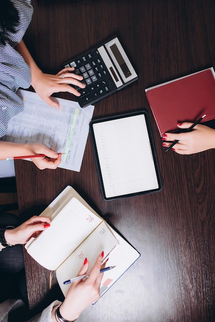 Il calcolatore del blocco note e le mani dei dipendenti sul concetto di business da tavolo